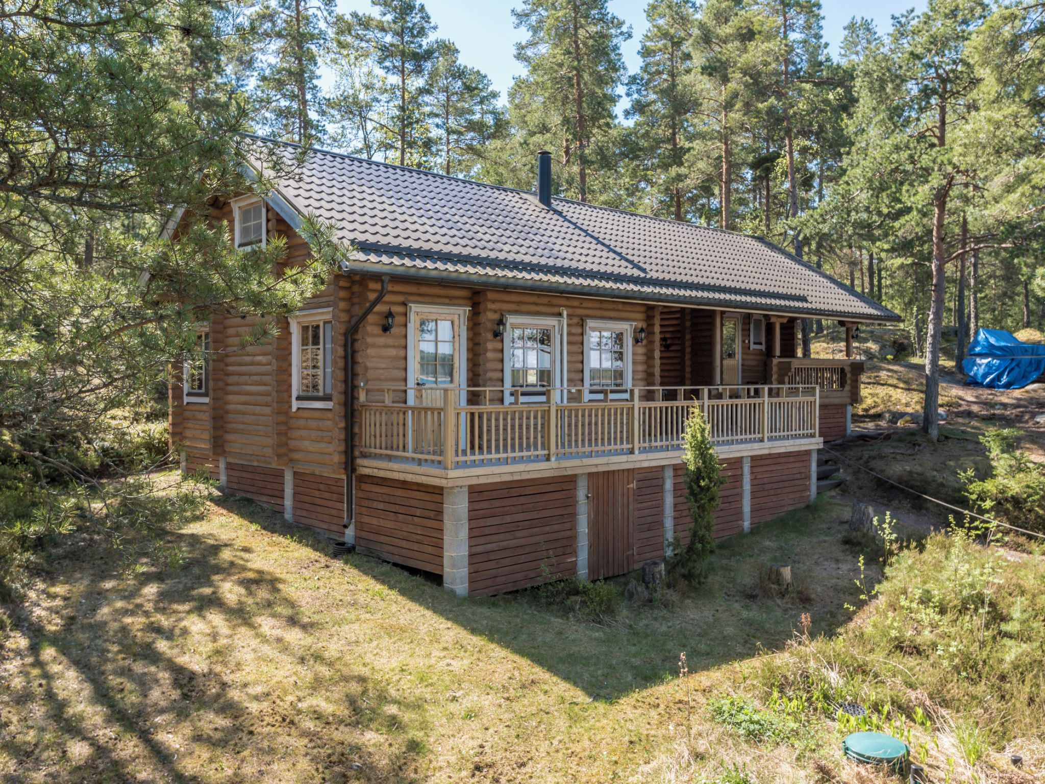 Une cabane en bois dotée d’un balcon, entourée d’arbres.