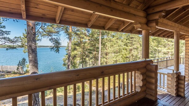 Une terrasse en bois avec une rambarde donnant sur un lac et une forêt.