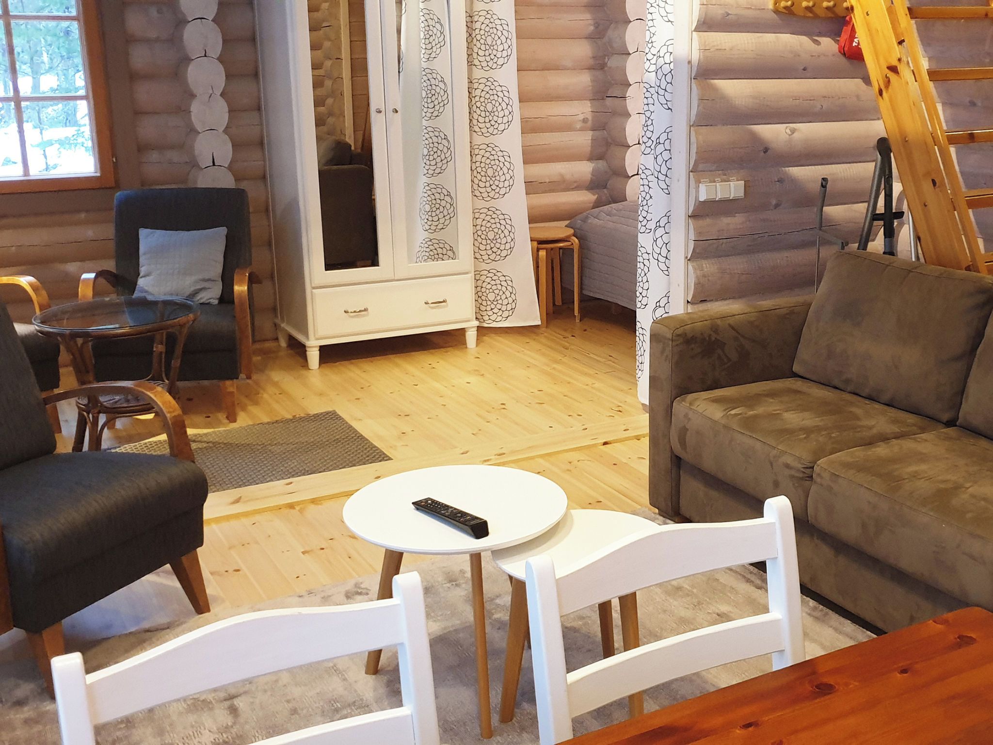 A log cabin interior with a sofa, chairs, a cabinet, and a table.