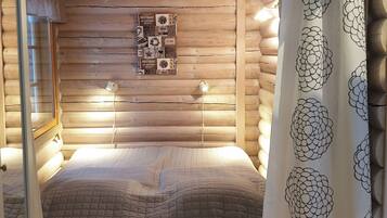 A log cabin room with a bed, two wall-mounted lamps, and a decorative wall piece.