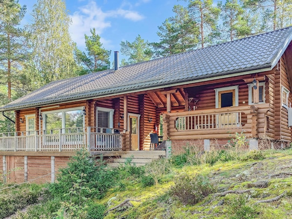 A log cabin with a porch, windows, and a chimney.