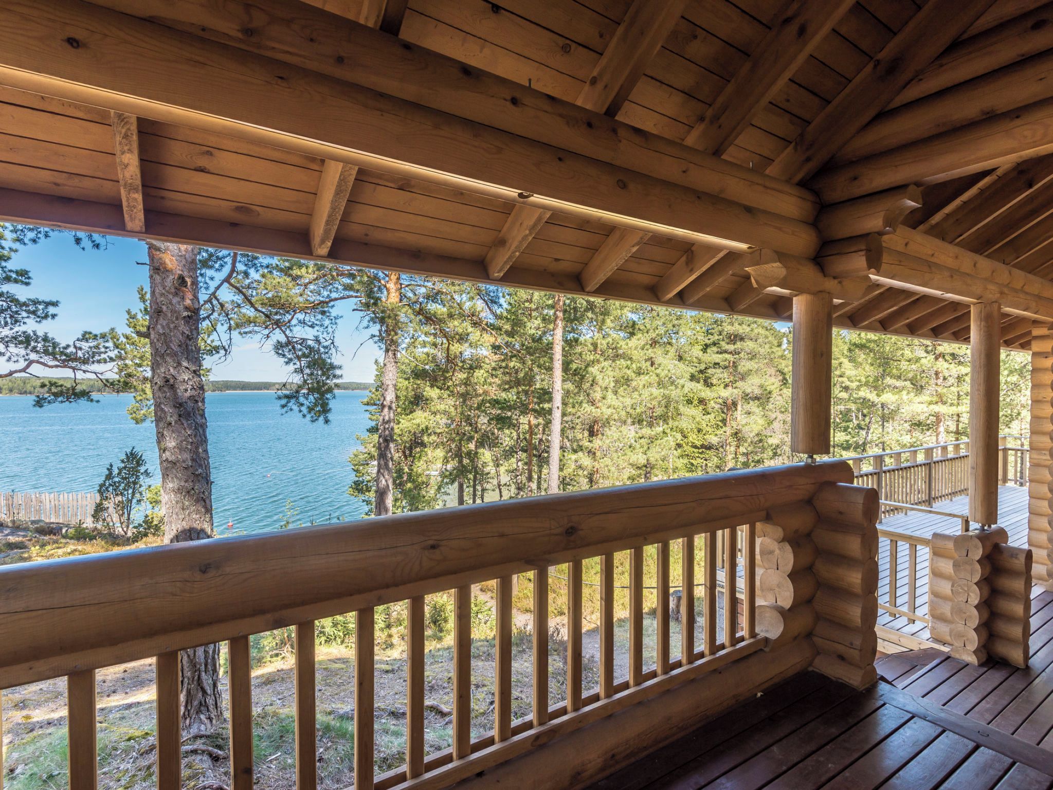Eine Holzterrasse mit Geländer, mit Blick auf einen See und Wald.