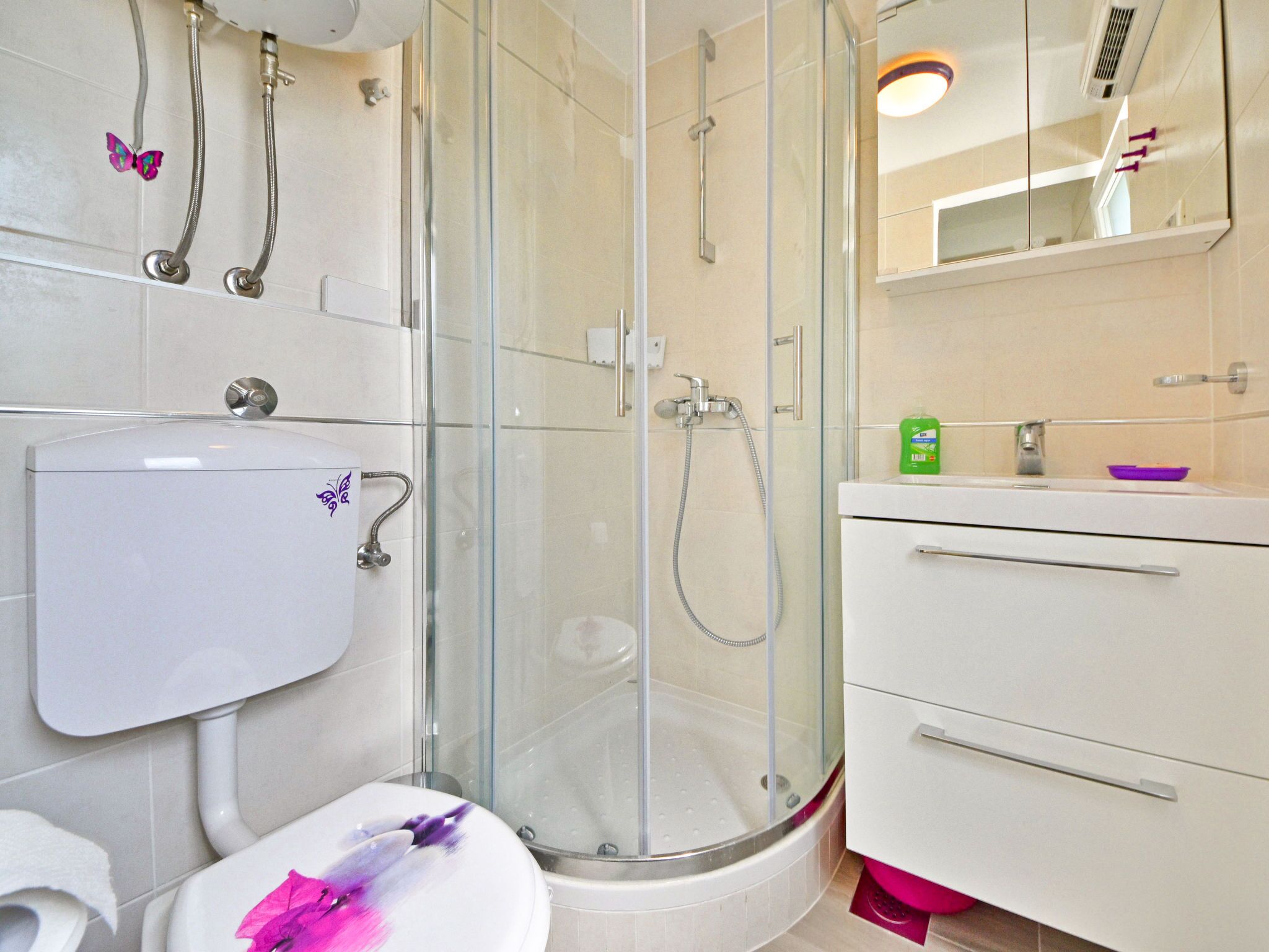 A modern bathroom with a glass-enclosed shower, a toilet, and a vanity with a mirror.