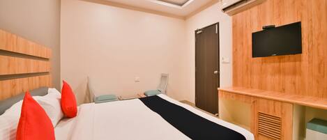 A modern hotel room with a large bed, a TV mounted on the wall, and a wooden cabinet.