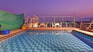 A swimming pool with a chevron pattern on the floor, surrounded by a wooden deck and metal railings. - Ardency Inn by Park Tree Udaipur (Udaipur)