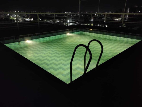 A rooftop swimming pool with a chevron pattern, surrounded by a railing, and overlooking a cityscape at night. - Ardency Inn by Park Tree Udaipur (Udaipur)
