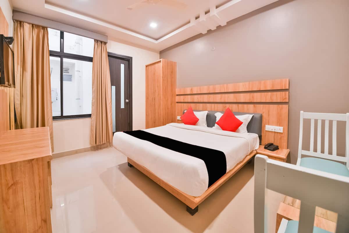 A modern hotel room with a wooden bed, a nightstand, a white chair, and a large window with curtains.
