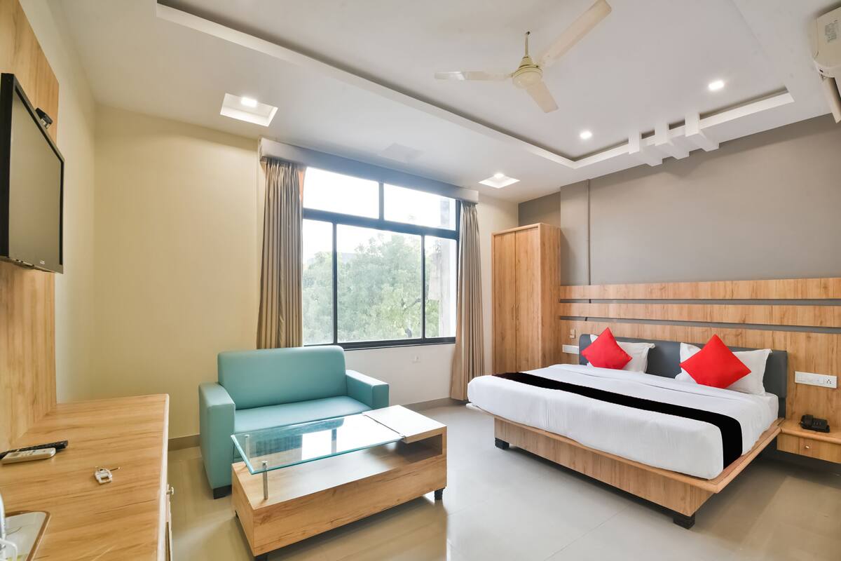 A modern hotel room with a bed, a sofa, a TV, and a desk.