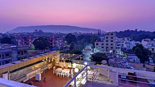 A rooftop terrace with a dining area, a view of the cityscape, and a hill in the background. - Ardency Inn by Park Tree Udaipur (Udaipur)
