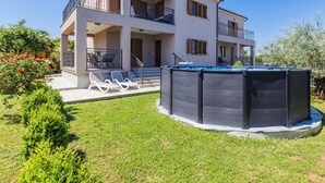 Una casa de dos pisos con balcón, piscina y jardín.