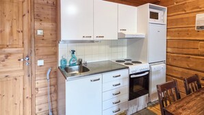 Una cocina compacta con armarios blancos, un lavamanos, una estufa y un horno.