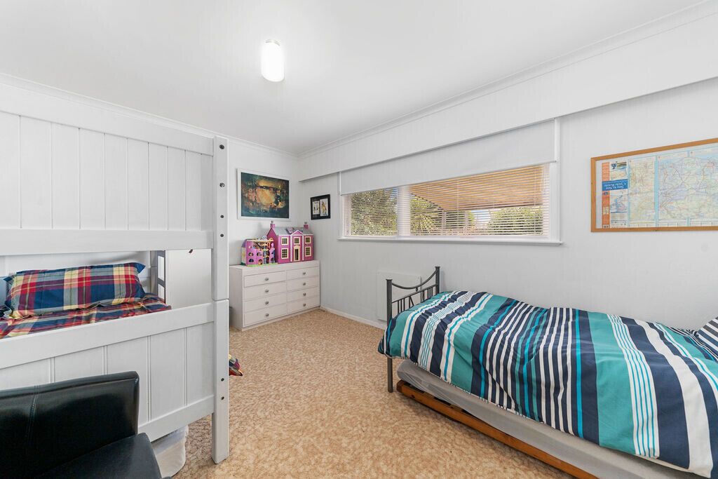 A bedroom with bunk beds, a dresser, a window with blinds, and a map on the wall.