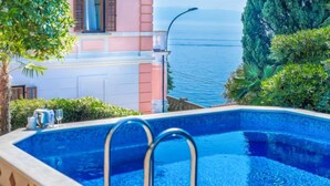 Ein Pool mit Meerblick, ein Gebäude mit rosa und weißen Wänden sowie eine Palme.