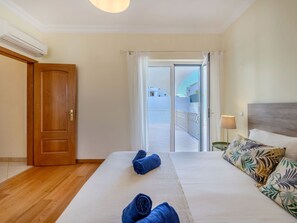 A hotel room with a bed, a nightstand, a lamp, and a view of the outside balcony. - Colibri by Interhome (Gale)