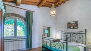 Quarto com cama, janela com cortinas, luminária pendente e um quadro na parede.