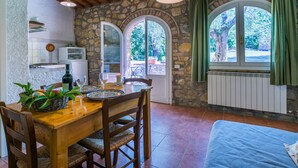 Uma cozinha rústica com paredes de pedra, vigas de madeira e um espaço de jantar com mesa posta para dois.