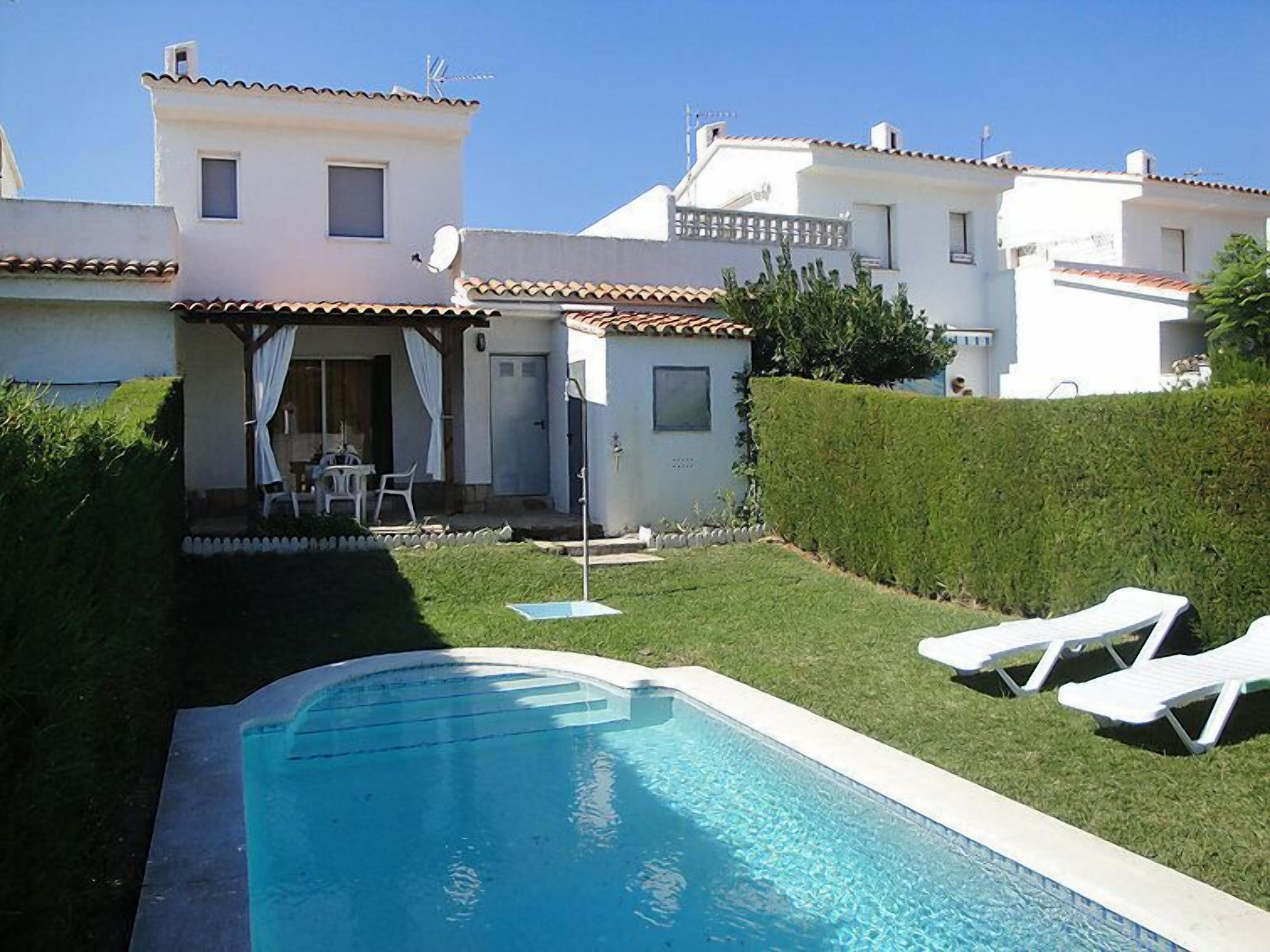 A residential property with a swimming pool, a patio with outdoor furniture, and a well-maintained garden.