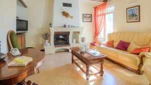 A cozy living room with a fireplace, a sofa, a wooden coffee table, and a television. - de la Roque by Interhome (Carpentras)