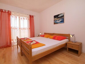 A bedroom with a wooden bed, a nightstand, a lamp, and a painting on the wall.