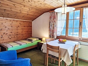 Een knus vakantiehuisje met een vide, een eettafel en uitzicht op een besneeerd landschap door grote ramen.