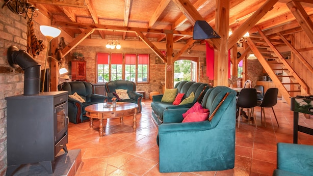 Un intérieur rustique en bois, avec une cheminée, des canapés en cuir et un coin repas.