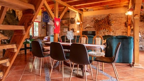 Un coin repas rustique avec des poutres en bois, un mur en pierre et un tigre empaillé.