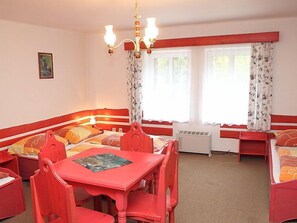 A room with a red and white color scheme, featuring a bed with a headboard, a dining table with chairs, and a chandelier. - Karlovka by Interhome (Janov nad Nisou)
