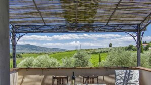 A covered outdoor dining area with a table and chairs, overlooking a scenic landscape with hills and trees. - Borgo Fontana by Interhome (Vinci)
