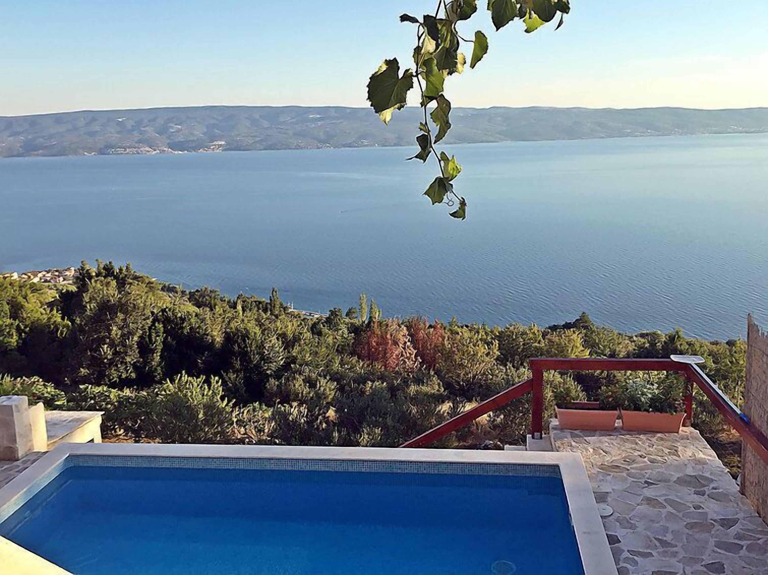 A swimming pool with a view of a large body of water and surrounding greenery.
