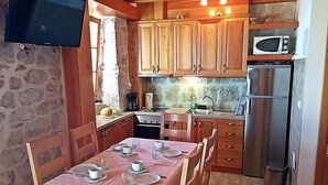 A cozy kitchen with wooden cabinets, a dining table set for four, a microwave, and a refrigerator.