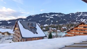 Un albergo con tetto spiovente imbiancato dalla neve, sullo sfondo montagne innevate.