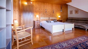 Una camera da letto con pannelli in legno, un letto matrimoniale, due comodini con lampade, una sedia, un divano e un tappeto decorato.