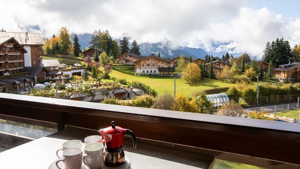 Un rifugio alpino con edifici in stile chalet, una sala da pranzo con tavolo e set da caffè, e vista sul paesaggio circostante.