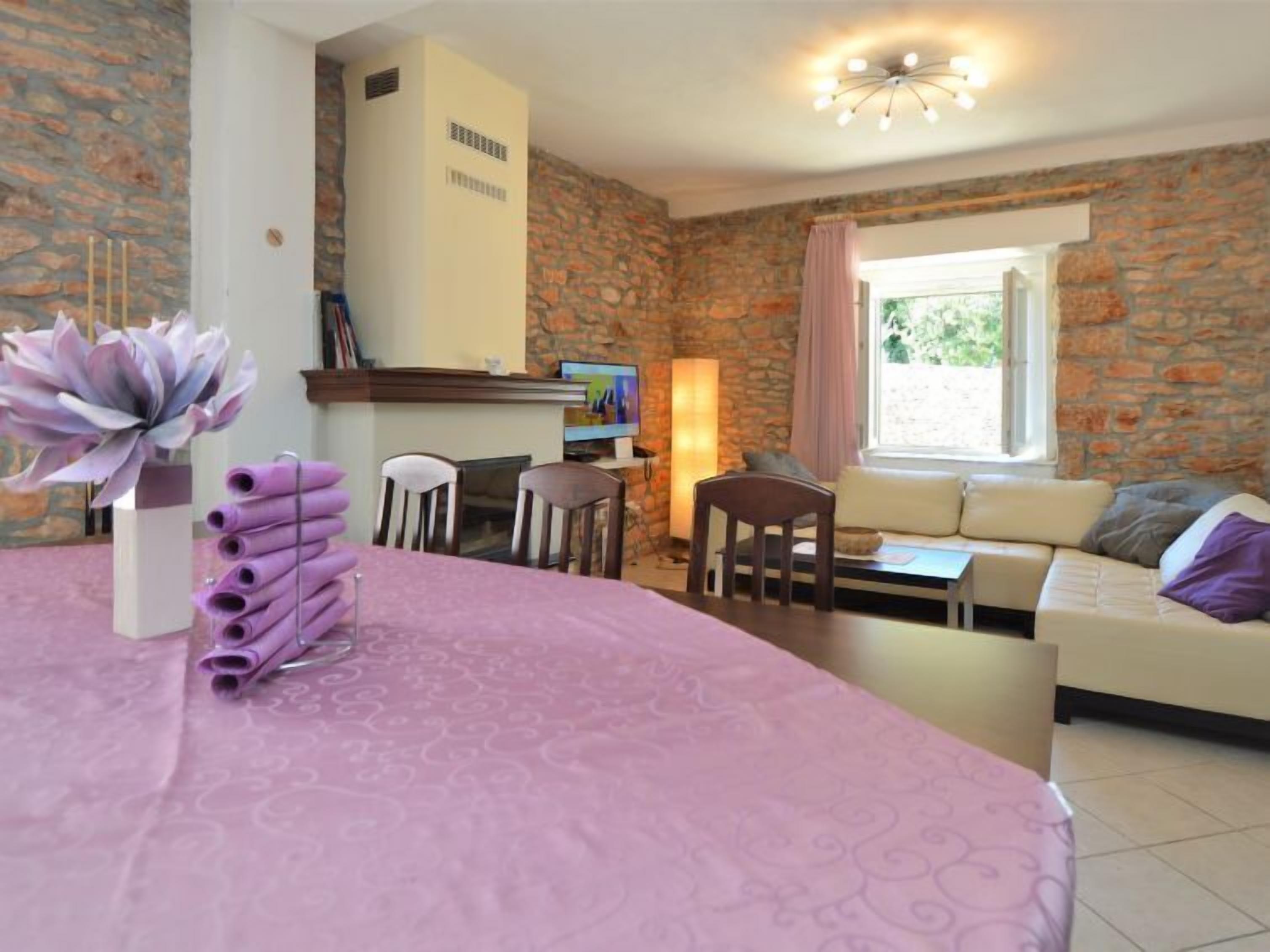 Een gezellige woonkamer met een stenen muur, een bank, een eettafel met stoelen en een open haard.