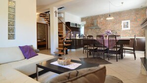 A modern living room with a sofa, coffee table, and a dining area with chairs and a table. A staircase leads to an upper level. - Vacation home Marija by Interhome (Oklaj)