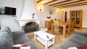 Una sala de estar acogedora con chimenea, un comedor y un televisor montado en la pared.