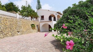 Un patio con piso de piedra, un edificio blanco con arcos y un muro de piedra.