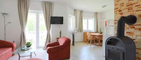 Ein Wohnzimmer mit Kamin, roten Sofas, einem Glastisch und einem Essbereich mit Holztisch und Stühlen.