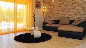 Ein modernes Wohnzimmer mit Steinwand, schwarzem Sofa und Glastisch.