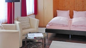Una habitación con cama, una silla, una mesita y un armario.