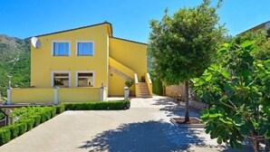 Un bâtiment jaune avec une allée pavée et un escalier menant à une porte.