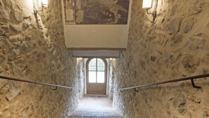 Eine Steintreppe mit Blick nach draußen durch ein rundbogenförmiges Fenster am oberen Ende.