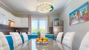 Una cocina moderna con armarios blancos, encimera azul y refrigerador de acero inoxidable.