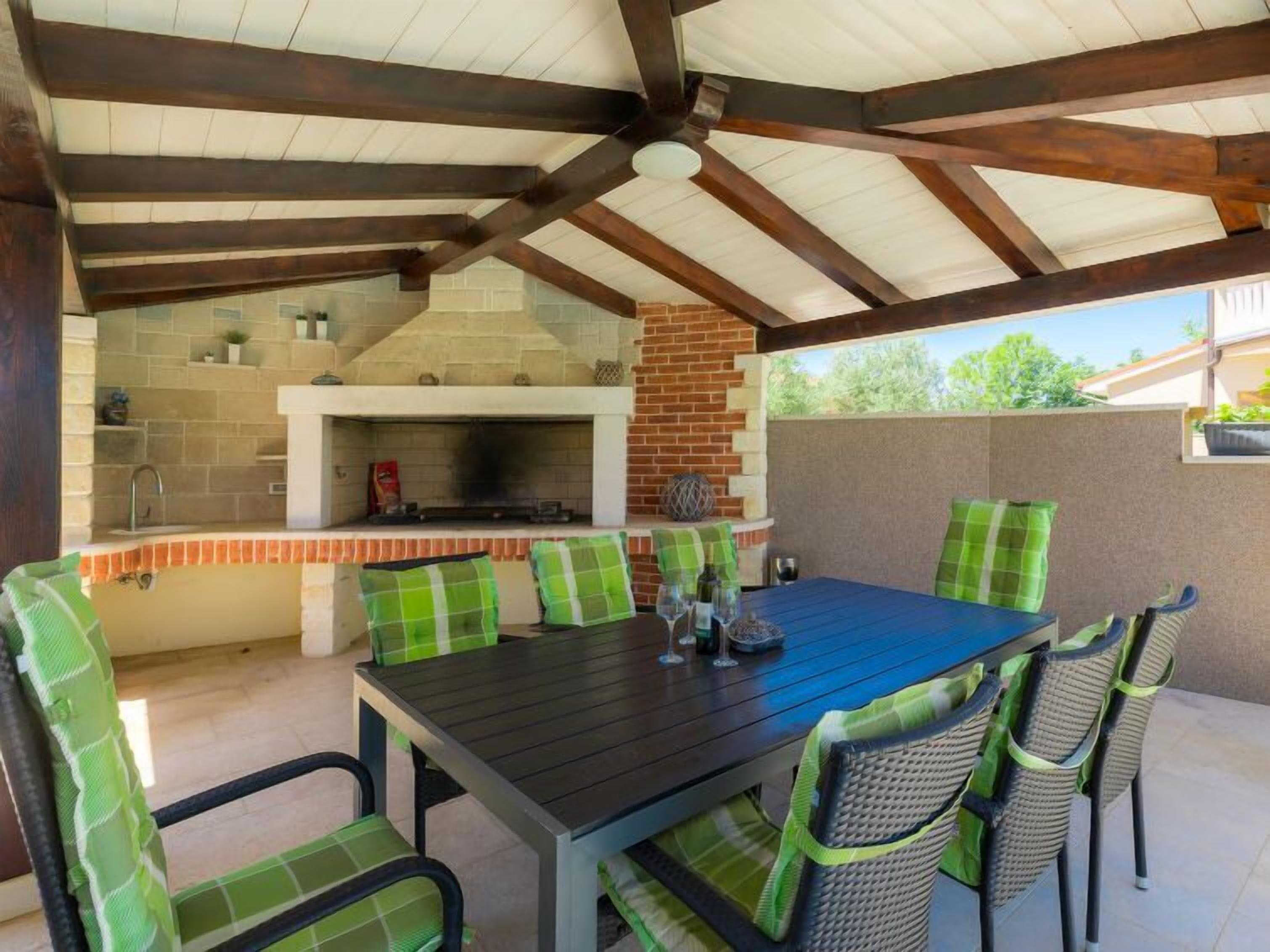An outdoor patio with a brick fireplace, a dining table, and wicker chairs.