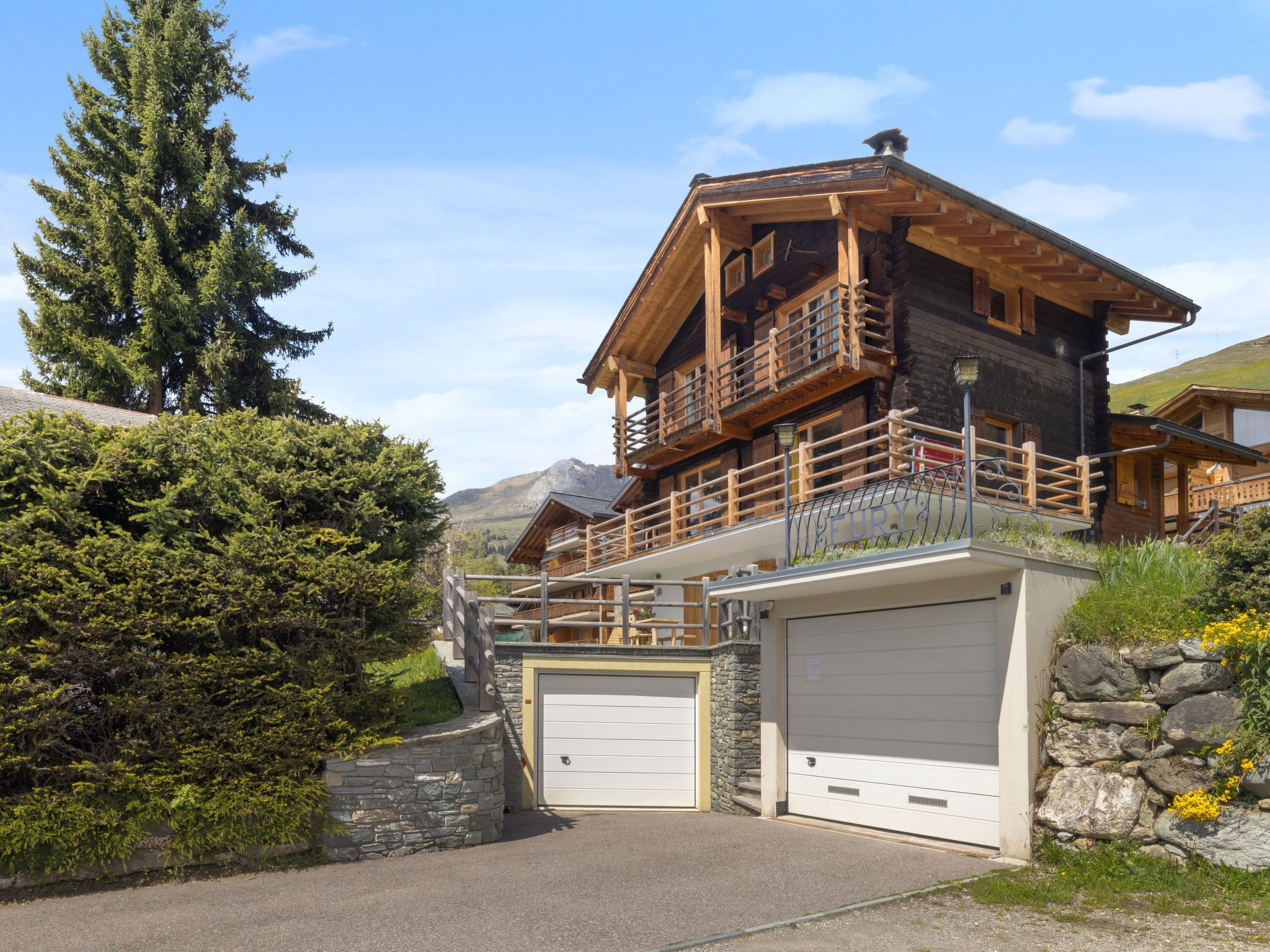 Eine Blockhütte mit Balkon, Steinmauern und Garage.