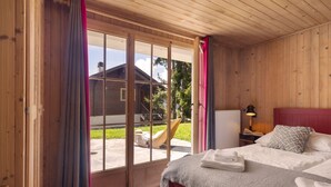 Ett rum med träpanel, en säng, ett fönster och utsikt över ett hus utanför.