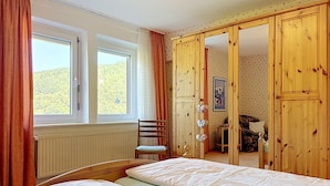 Une chambre avec deux lits, une chaise, une armoire et une fenêtre avec des rideaux.