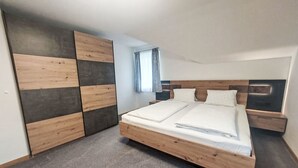 Ett sovrum med en stor säng, en garderob med en mörk träpanel och ett fönster med gardiner.