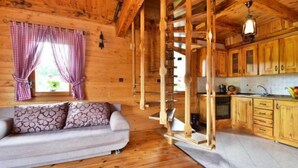 Ein Interieur einer Holz-Blockhütte mit einer Couch, einer Treppe und einem Küchenbereich.