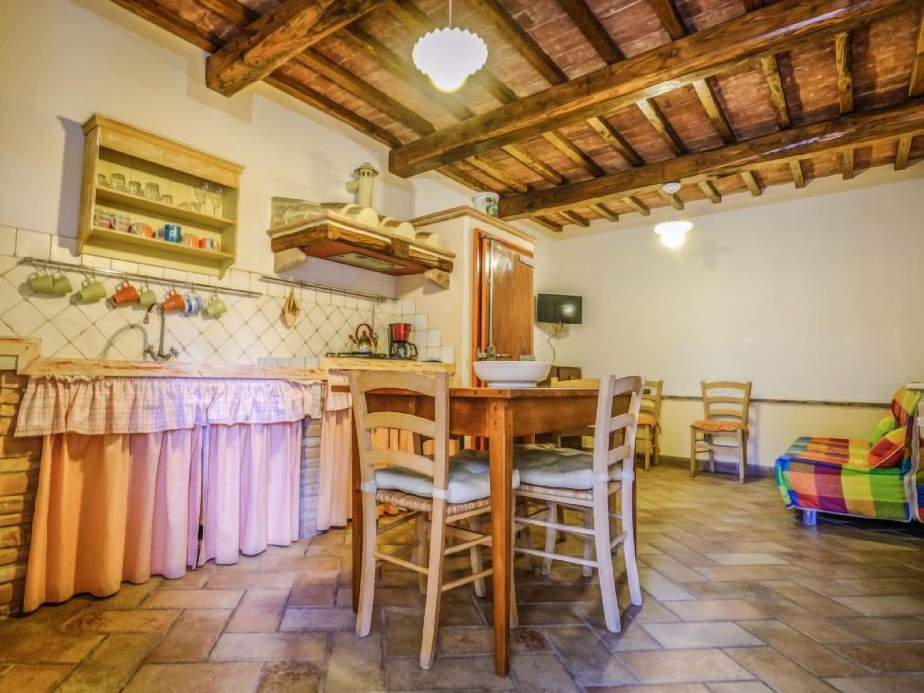 Eine rustikale Küche mit Holztisch, Stühlen und einer gefliesten Spritzschutzwand.